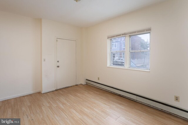 spare room with light wood-type flooring and a baseboard heating unit