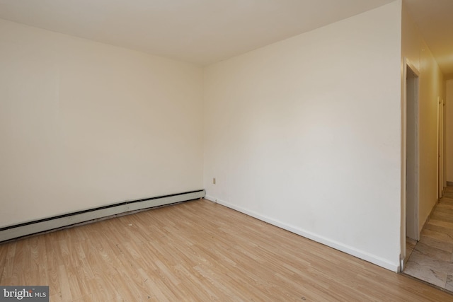 unfurnished room with a baseboard radiator and light hardwood / wood-style floors