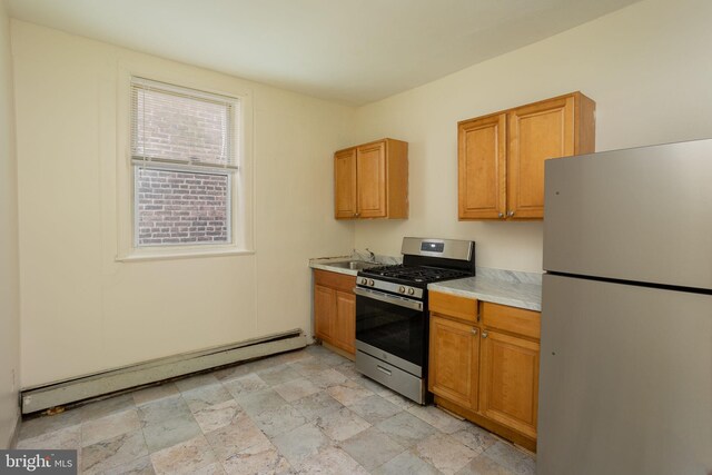 kitchen featuring white fridge, baseboard heating, stainless steel gas stove, and sink