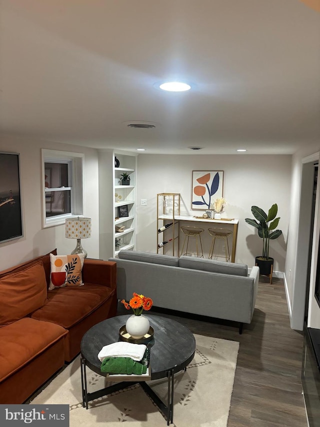 living room with built in shelves and hardwood / wood-style flooring