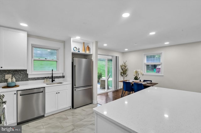 kitchen featuring appliances with stainless steel finishes, sink, decorative backsplash, and white cabinetry