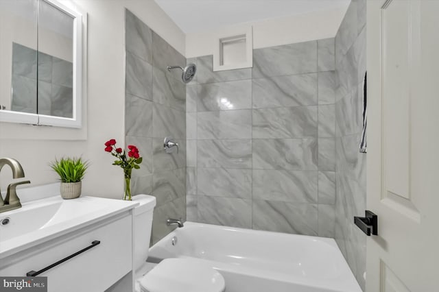 full bathroom featuring tiled shower / bath combo, vanity, and toilet