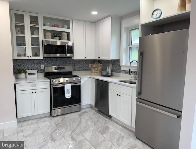 kitchen featuring stainless steel appliances, backsplash, sink, and white cabinetry