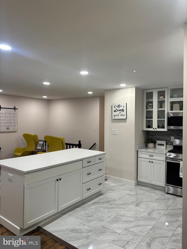 kitchen with a barn door, white cabinetry, stainless steel appliances, and backsplash