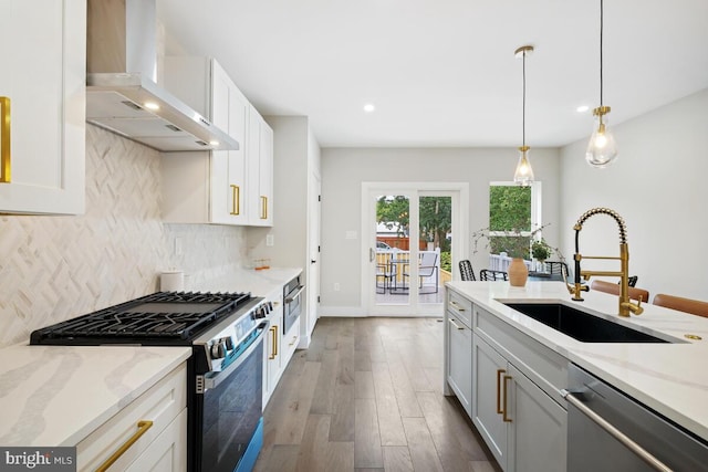 kitchen with light stone counters, dark hardwood / wood-style floors, white cabinetry, wall chimney exhaust hood, and appliances with stainless steel finishes