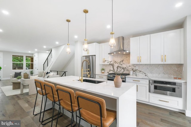 kitchen with hanging light fixtures, wall chimney exhaust hood, dark hardwood / wood-style floors, and stainless steel appliances