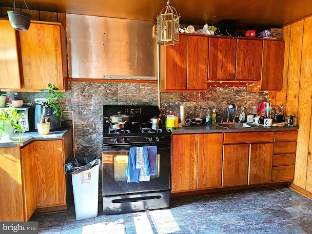 kitchen featuring tasteful backsplash, black range with gas cooktop, sink, and hanging light fixtures