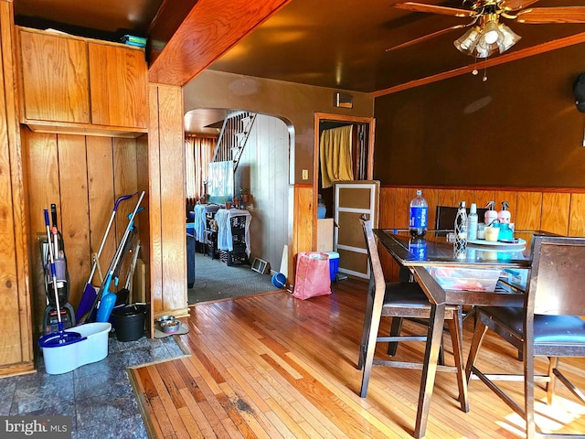 dining space featuring ceiling fan, wooden walls, and hardwood / wood-style flooring