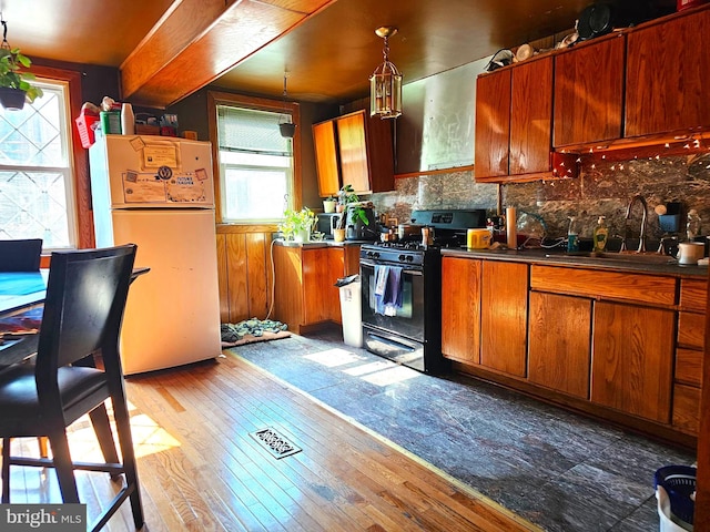 kitchen with backsplash, gas stove, sink, dark wood-type flooring, and white refrigerator