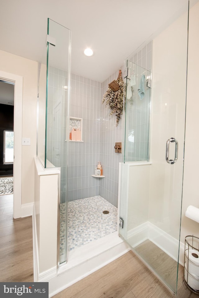 bathroom featuring wood-type flooring and a shower with door