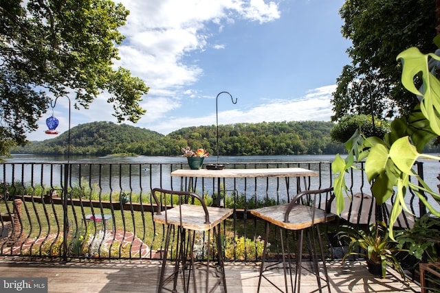 wooden deck featuring a water view and a lawn