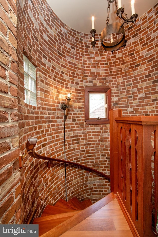 interior space with brick wall and hardwood / wood-style floors