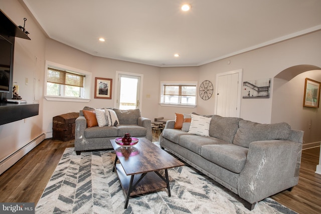 living room with a wealth of natural light, baseboard heating, and dark hardwood / wood-style floors