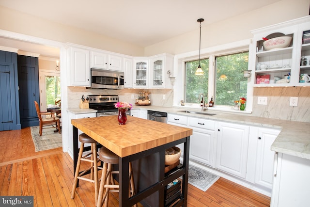 kitchen with light hardwood / wood-style flooring, sink, appliances with stainless steel finishes, and white cabinetry