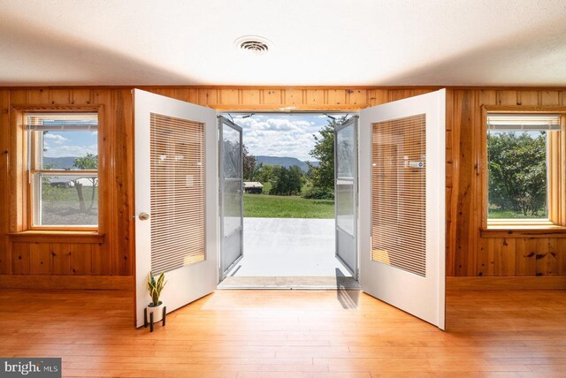 doorway with light wood-type flooring and wood walls