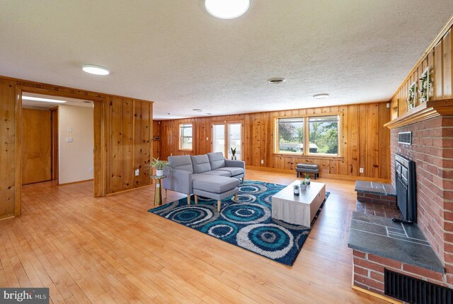 living room featuring a textured ceiling, wooden walls, hardwood / wood-style flooring, and a fireplace