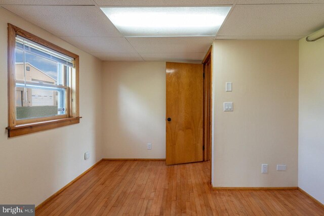 unfurnished room with a drop ceiling and light hardwood / wood-style floors