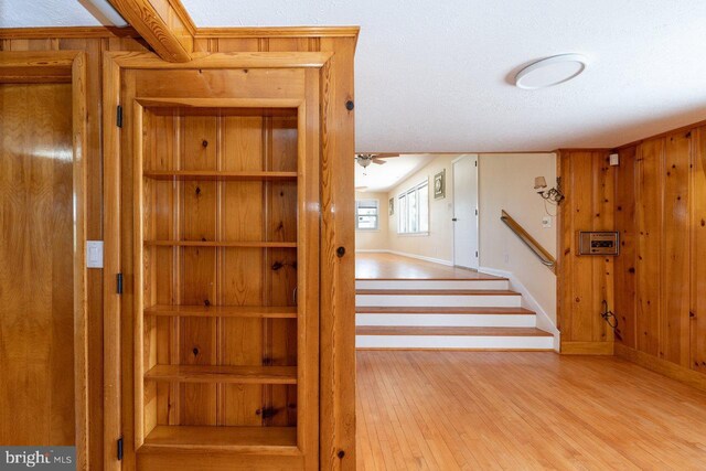 stairway featuring a textured ceiling, hardwood / wood-style floors, and wooden walls