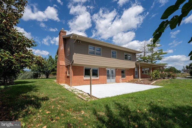 back of house with a lawn and a patio