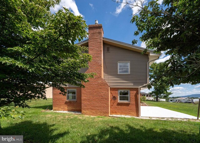 view of side of home with a yard and a patio