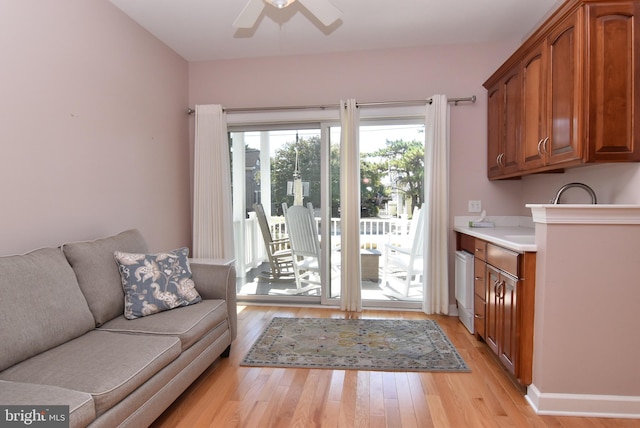 living area with baseboards, a ceiling fan, and light wood-style floors