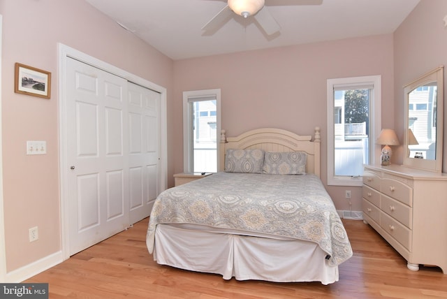 bedroom with light wood-type flooring, a closet, ceiling fan, and baseboards