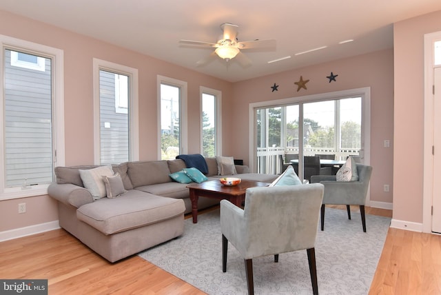 living room featuring light wood-type flooring, baseboards, and a ceiling fan