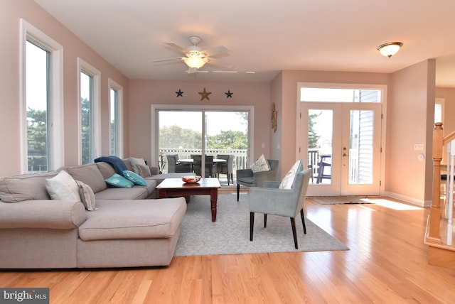 living area featuring french doors, stairway, light wood-type flooring, and baseboards