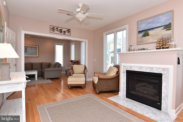 sitting room with a high end fireplace, ceiling fan, and hardwood / wood-style floors