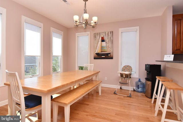 dining area with light hardwood / wood-style flooring and a notable chandelier