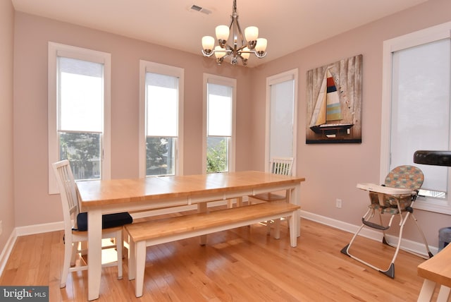 dining room featuring light wood finished floors, baseboards, visible vents, and an inviting chandelier