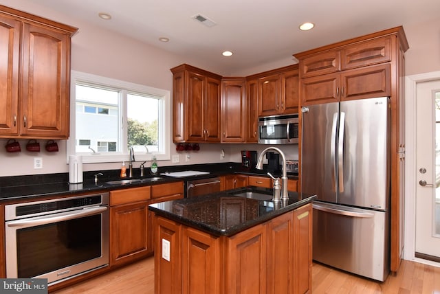 kitchen with visible vents, a center island with sink, appliances with stainless steel finishes, and a sink