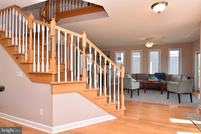 staircase with ceiling fan, wood finished floors, and baseboards