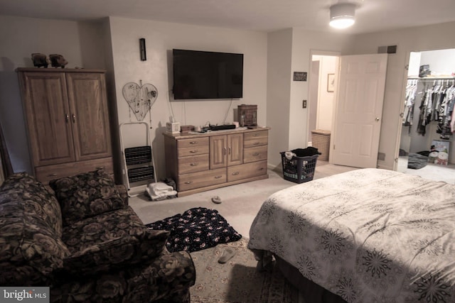 carpeted bedroom with a walk in closet and a closet