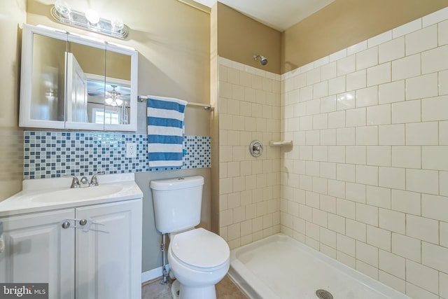 bathroom with vanity, tiled shower, tile walls, toilet, and decorative backsplash