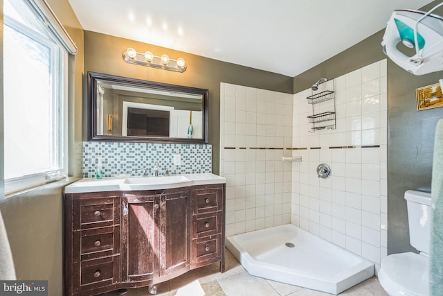 bathroom featuring tile patterned flooring, toilet, tiled shower, tasteful backsplash, and vanity