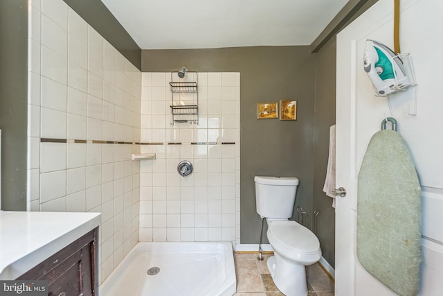 bathroom with tiled shower, vanity, toilet, and tile patterned flooring