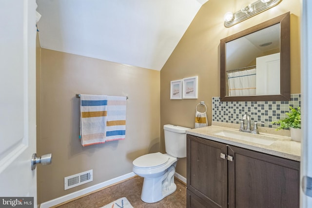 bathroom with tile patterned flooring, toilet, lofted ceiling, decorative backsplash, and vanity