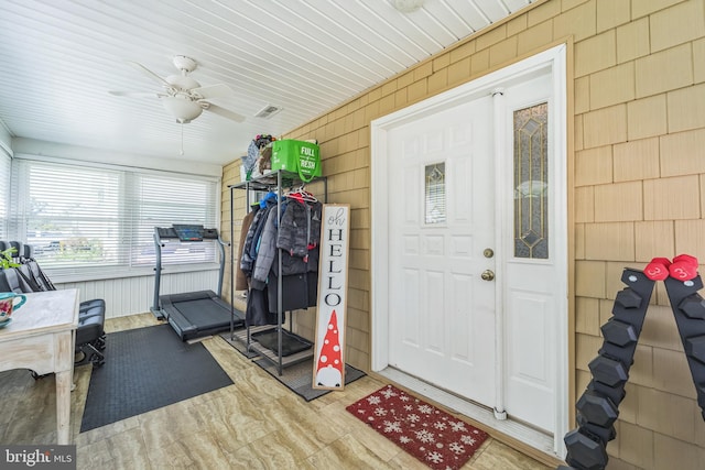 exercise area with wooden ceiling, ceiling fan, and wooden walls