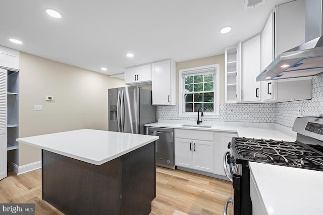 kitchen featuring light wood-type flooring, stainless steel appliances, wall chimney exhaust hood, and sink