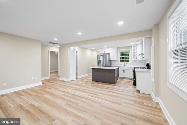 kitchen with stainless steel fridge with ice dispenser, a kitchen island, white range, and light wood-type flooring