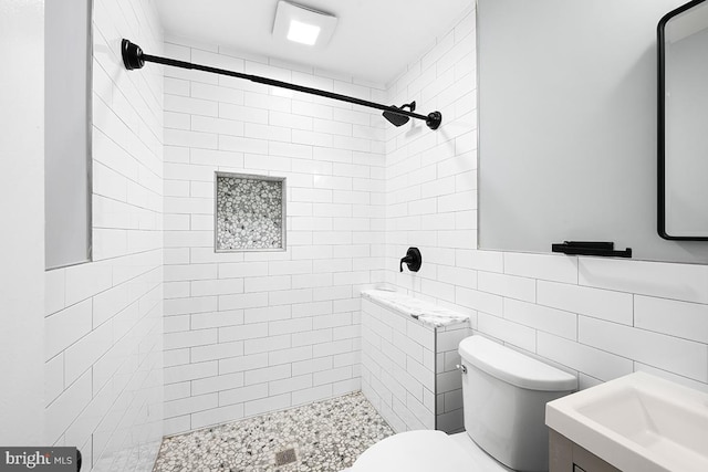 bathroom featuring tiled shower, vanity, tile walls, and toilet