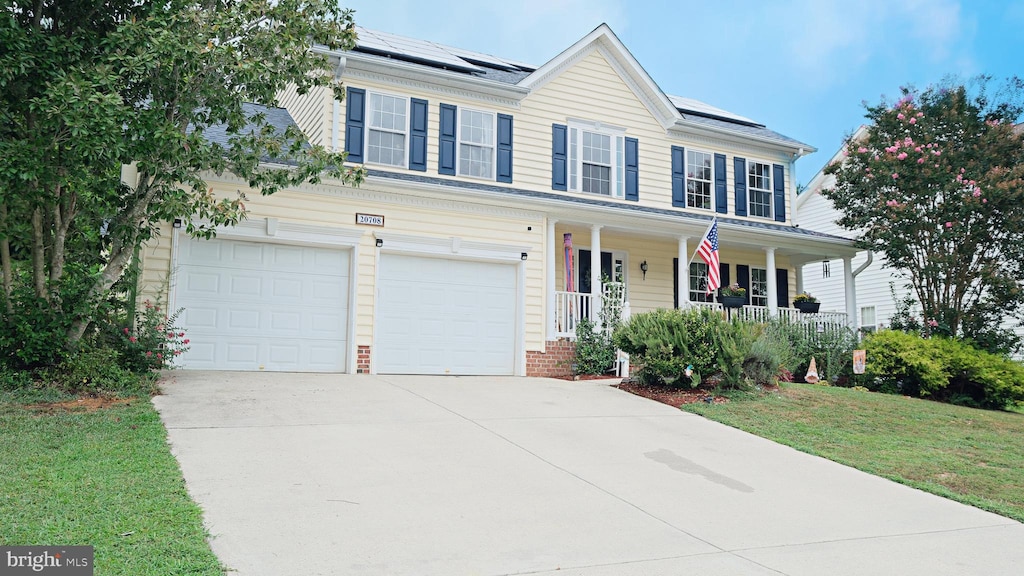 view of front facade with a front yard, a garage, a porch, and solar panels