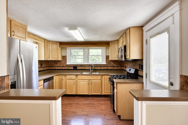 kitchen with stainless steel appliances, decorative backsplash, dark wood-type flooring, a sink, and a peninsula