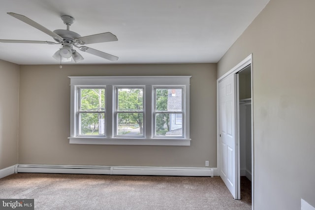 unfurnished bedroom with a baseboard heating unit, multiple windows, carpet, and a closet