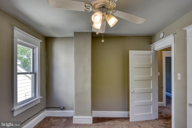 carpeted spare room with a ceiling fan and baseboards