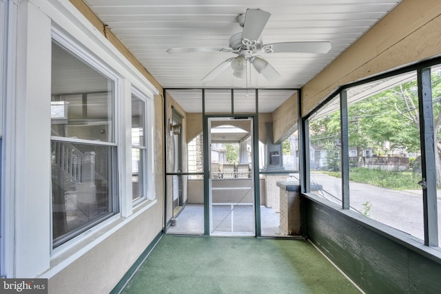 unfurnished sunroom featuring a ceiling fan and a healthy amount of sunlight