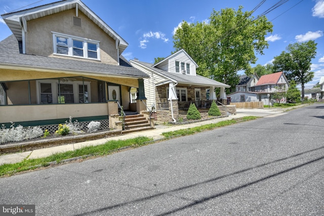 view of front of house featuring stone siding, a porch, and stucco siding