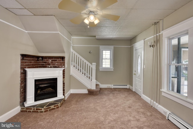 carpeted entrance foyer with a baseboard heating unit, a glass covered fireplace, stairway, and baseboards