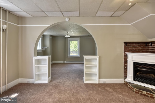 unfurnished living room with a paneled ceiling, carpet, a fireplace, and a baseboard heating unit